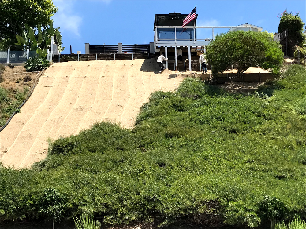 Crew working on hillside stabilization and retaining wall construction